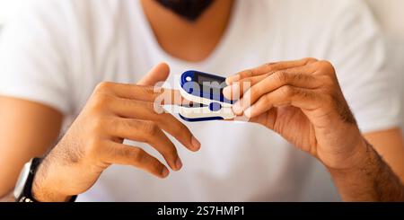 Unrecognizable man using pulse oximeter at home Stock Photo