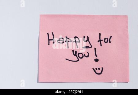 Handwritten 'Happy for You!' on a pink sticky note with a smiley face" Stock Photo