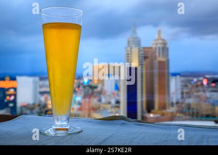 Las Vegas, Nevada, USA - October 24, 2021: A glass of cider overlooks the Strip skyline with New York New York, Excalibur, and Mandalay Bay hotels Stock Photo
