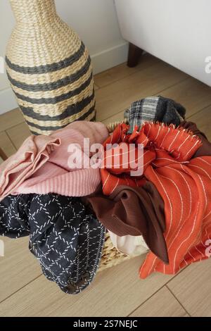 Assorted Colorful Textiles in a Wicker Basket Beside Decorative Woven Vase Stock Photo