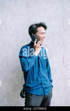 Happy young man having a phone call, smiling and engaged in conversation Stock Photo