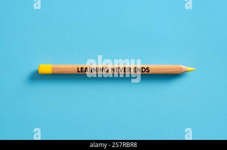 Single pencil with yellow tip over blue background with the motivational phrase learning never ends written on it Stock Photo