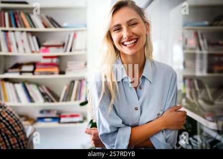Portrait of an attractive young african businesswoman smiling while standing by windows in office Stock Photo