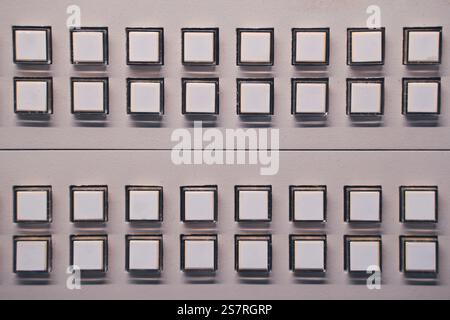 A closeup of multiple white buttons arranged in symmetrical rows on a control panel for a clean and modern look Stock Photo