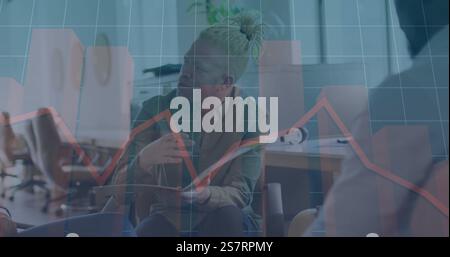 Businessman discussing documents with colleague, financial graph image over office scene Stock Photo
