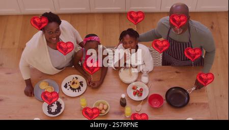 Smiling family enjoying breakfast together with red heart images floating over them Stock Photo