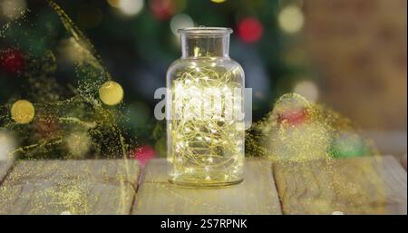 Glowing yellow particles image over jar with lights on wooden surface Stock Photo