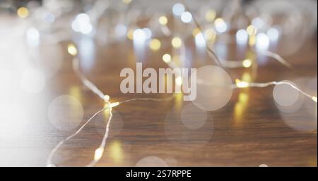 Fairy lights glowing over bokeh image on wooden surface Stock Photo
