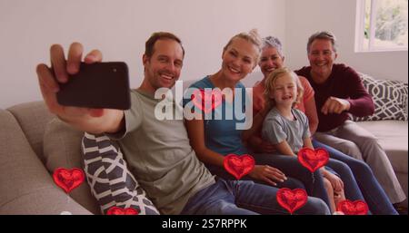 Taking selfie, family sitting on couch with floating red heart images Stock Photo