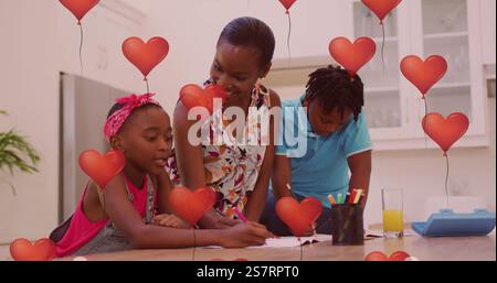 Red heart balloons image over family drawing together in kitchen Stock Photo