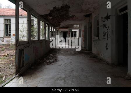 Deteriorated hallway in deserted hospital showing decay, vandalism, and neglect Stock Photo