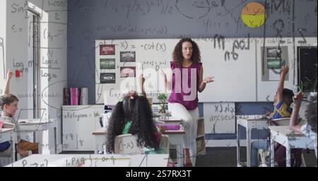 Image of mathematical equations over biracial female teacher with diverse schoolchildren Stock Photo
