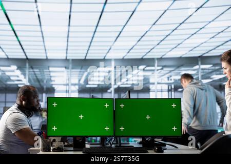 Green screen computer used by engineers working in high tech server hub processing vast amounts of data. Chroma key PCs used by workers to update servers controlling network resources Stock Photo