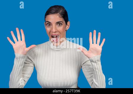 Business woman showing ten fingers with open mouth and surprised expression, isolated on blue studio background Stock Photo