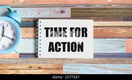 On a beautiful background there is a clock and a notepad with the text TIME FOR ACTION Stock Photo