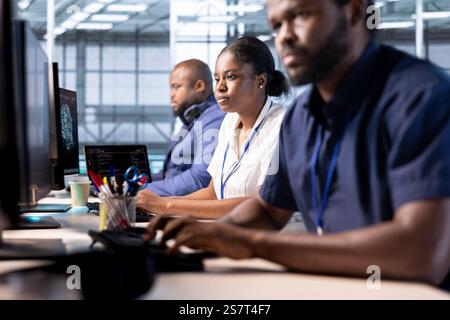 Team of data center engineers creating technical documentation for software applications. African american computer scientists working in server hub, maintaining databases Stock Photo