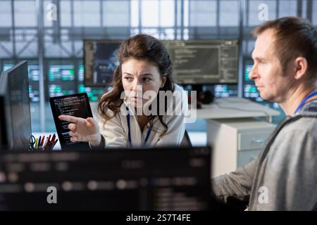 Team of data center programmers brainstorming ways of ensuring minimal downtime. Teamworking server farm colleagues using analytics to monitor performance and predict needed equipment upgrades Stock Photo