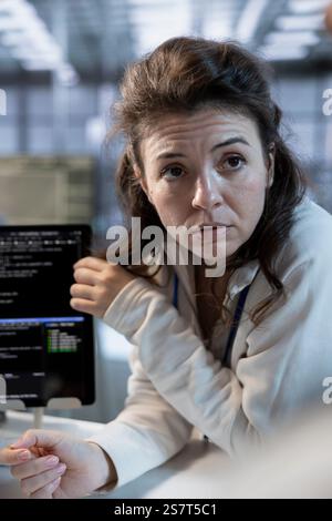 Technician using tablet to implement cybersecurity measures to protect data center assets. Woman in server hub monitoring and analyzing metrics with device to enhance operational effectiveness Stock Photo