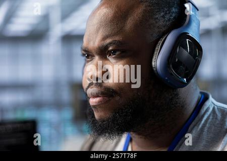 Close up of data center expert listening music and writing disaster recovery plans ensuring minimal downtime. Server farm technician wearing headphones uses analytics to monitor performance Stock Photo