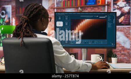 Person at home getting tasks done with AI program turning text prompt into videos. Woman using computer to make use of text to video artificial intelligence generative models, camera B Stock Photo
