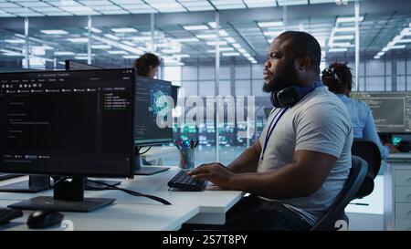 Teamworking colleagues updating AI systems, writing intricate binary code scripts on PC and laptop. Team of engineers using programming to upgrade artificial intelligence simulation model, camera B Stock Photo
