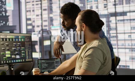 Manager correcting programmer mistakes while conducting code review to fix errors, identifying technical issues with company software. Team leader supervising IT staff member optimizing code, camera A Stock Photo