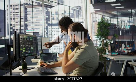 Manager correcting programmer mistakes while conducting code review to fix errors, identifying technical issues with company software. Team leader supervising IT staff member optimizing code, camera B Stock Photo