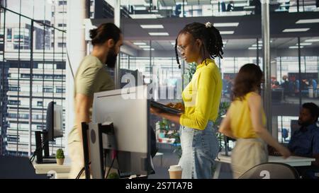 Computer scientist working, doing software debugging using notebook, troubleshooting errors. Woman standing in office, fixing coding issues using laptop, solving tasks, camera B Stock Photo