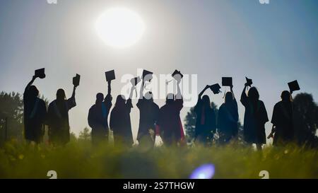 Excited high school graduates joyfully toss their caps in the air, celebrating their academic success Stock Photo