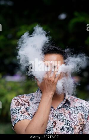 cigarettes steam Close up of a young man exhaling a cloud of steam or smoke with an  electronic cigarette Stock Photo