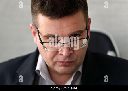 Stern Middle Age Man in Suit looking over Spectacles. A businessman man in glasses with a serious look looks piercingly at the camera. Stock Photo