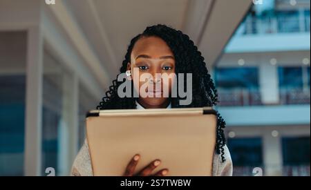 Focused corporate professional using a tablet in a modern business environment. The image captures a sense of concentration and engagement in technolo Stock Photo