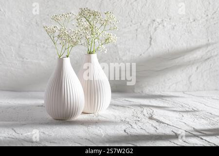 White vase with flowers on a stone background. Minimalist scene as a background with space for text. Stock Photo