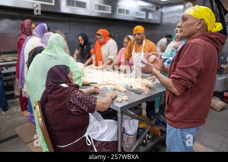 Sikh volunteers make roti bread for distribution in their langar communal kitchen. At a temple in Richmond Hill, Queens, New York. Stock Photo