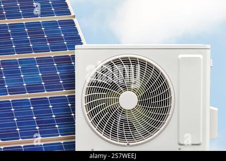 Air-source heat pump with solar panel in front of a blue sky Stock Photo