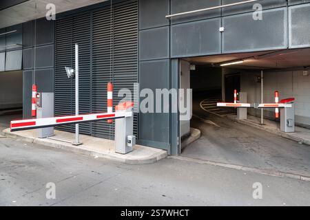 Modern parking garage entrance featuring automated barriers, security measures, and a streamlined urban infrastructure Stock Photo