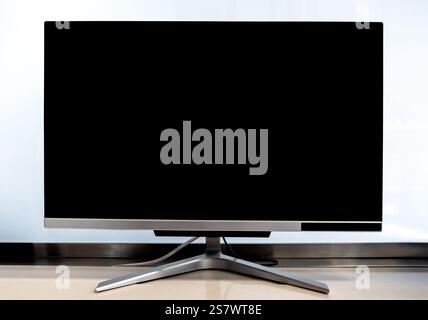 Empty black LCD screen of modern computer monitor on the table isolated on white background in office. Blank black display of computer in workplace. Stock Photo