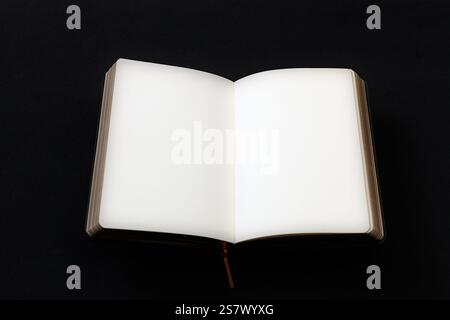 Open blank notebook with crisp white pages against a black background, symbolizing creativity and potential. Stock Photo