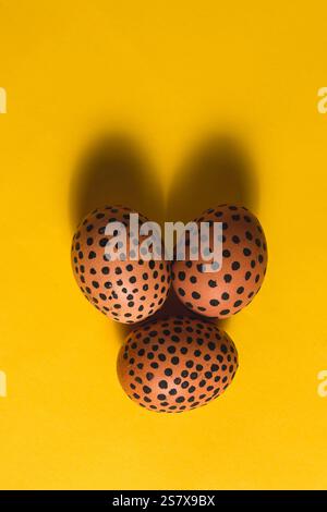 Vertical image of Easter eggs in Easter bunny shape. Flat lay on yellow background. Design for greeting card Stock Photo