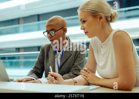 Two young lawyers are actively collaborating on a project in a bright, modern office setting. They are focused and engaged, working together on a lapt Stock Photo