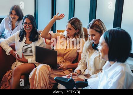 A group of female students engaged in a relaxed study session, enjoying the informal learning environment, featuring one student raising her hand in p Stock Photo