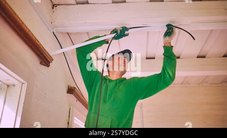 An electrician conducts wiring in a wooden house. Stock Photo