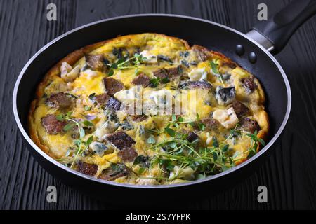 omelette with blue cheese, rye croutons and fresh thyme on a skillet on black wooden table, close-up Stock Photo