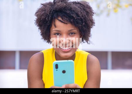 Smiling african american Young Woman Holding Smartphone Outdoors Stock Photo