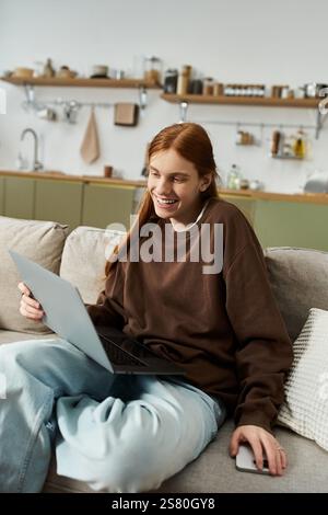 A young guy with long red hair relaxes in his stylish apartment while using a laptop. Stock Photo