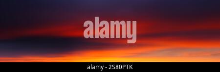 Afterglow in panoramic sky with smooth clouds, with surreal and almost abstract beauty in deep orange and purple Stock Photo