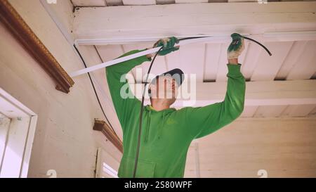 An electrician conducts wiring in a wooden house. Stock Photo
