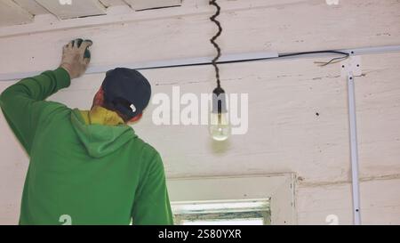 An electrician conducts wiring in a wooden house. Stock Photo