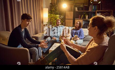 Teen boy talks to psychologist, discussing concerns, while his family listens attentively in the background. Maintaining productive communication Stock Photo