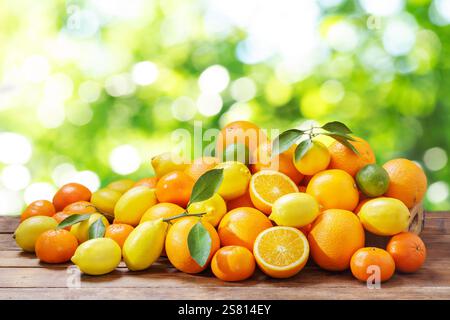 Mix of fresh ripe citrus fruits with leaves on wooden table. Mandarin oranges fruit or tangerines, oranges, lemons and limes Stock Photo